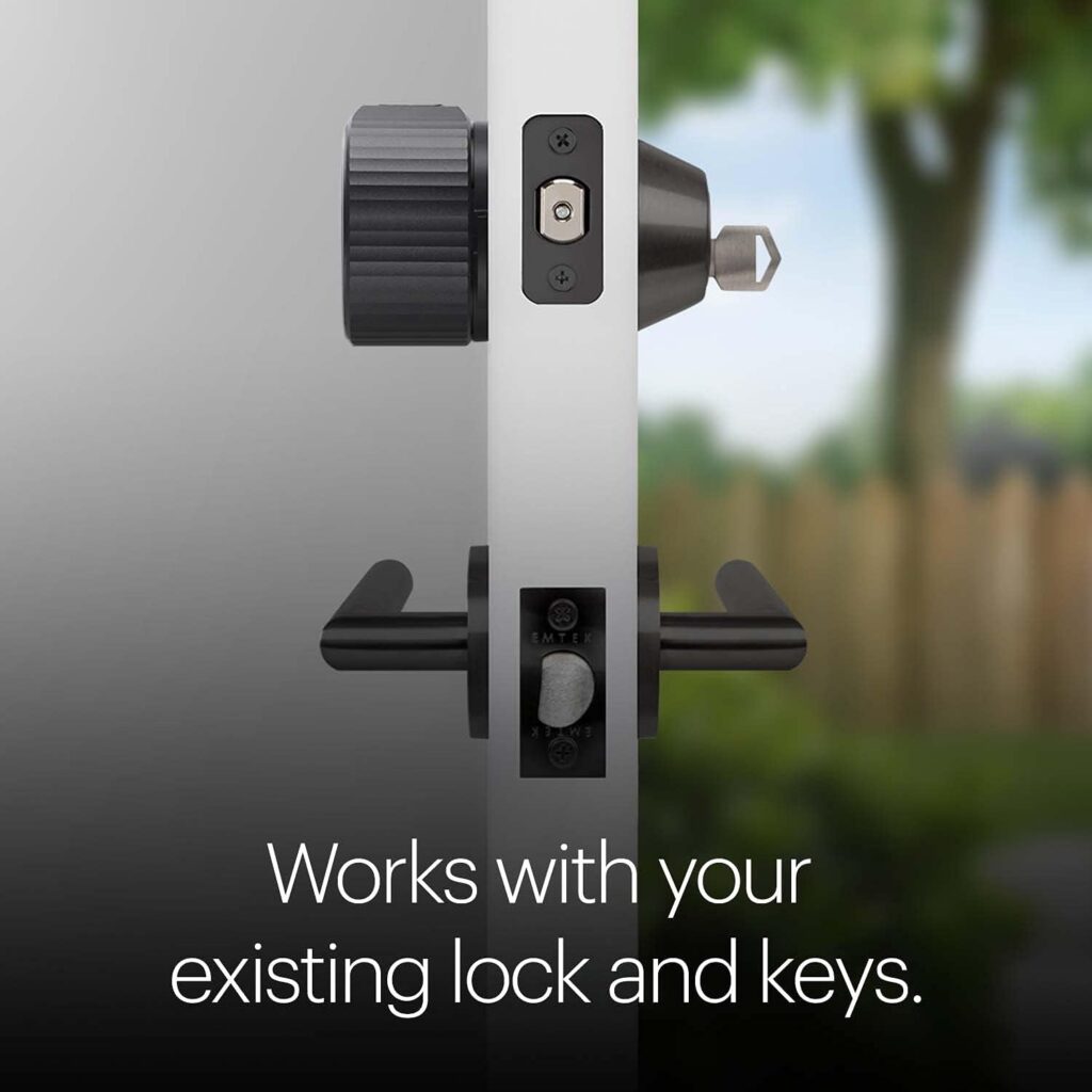Close-up side view of a door with a smart lock device installed on a deadbolt above a traditional handle, created using Elementor. Text reads: Works with your existing lock and keys. A garden and fence are visible outside. alwaysagift.co.uk