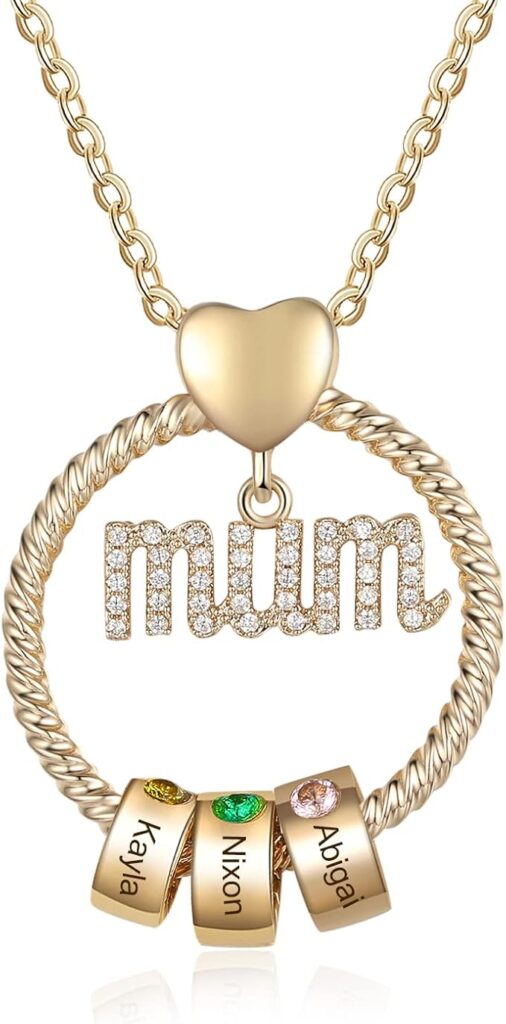 A gold necklace features a heart charm, a textured circular pendant, and the word mum in sparkly letters. Three gold rings at the bottom, styled with Elementor inspiration, display engraved names—Kaila, Nixon, and Abigail—with colored stones. alwaysagift.co.uk